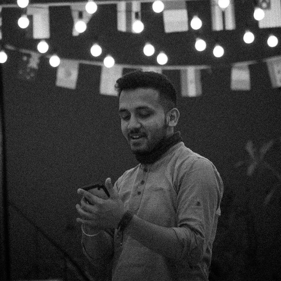 A professional videographer named Sam concentrating on filming an event with his camera, in a black and white photograph.