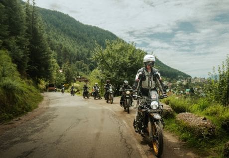 Motorcyclists on a premium Himalayas motorbike expedition riding through a lush green scenic route in the mountains.